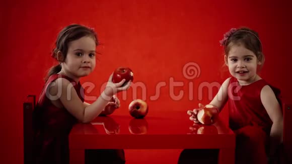 两个小女孩在红桌子上吃苹果视频的预览图