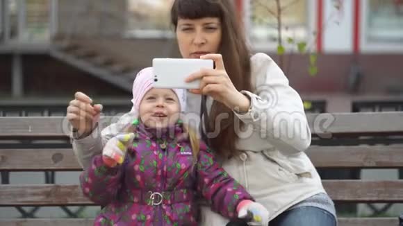 母亲和女儿坐在一条繁忙道路附近的长凳上带着sefi视频的预览图