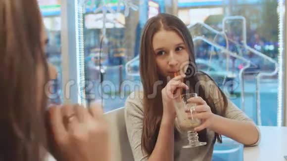 两个女学生的女朋友喝鸡尾酒在咖啡馆里聊天在城市街道的背景视图中秋天视频的预览图