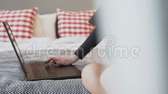 一个穿着黑色紧身衣带领的怀孕少女在家里的笔记本电脑上工作用手抚摸她的腹部视频的预览图