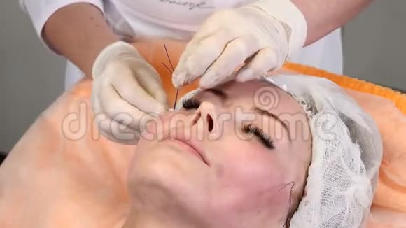 美容诊所年轻的女性客户得到螺纹面提升手套美容师给女性做面部抗衰视频的预览图