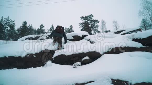 一位年轻的旅行者爬满了白雪的岩石悬崖视频的预览图