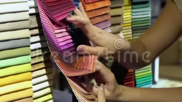 女人在架子上选择织物的颜色关闭织物样品女人帮助客户选择视频的预览图