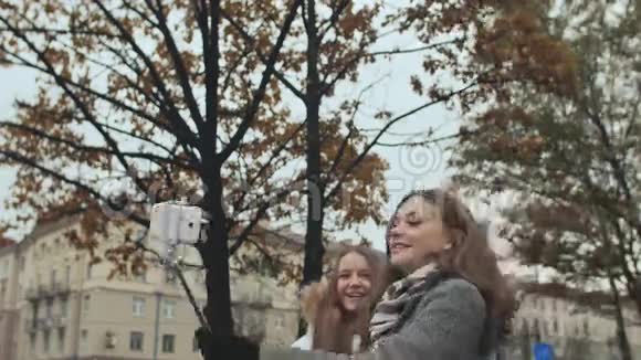 两个年轻的女孩朋友在一个城市的街道上做自我秋天视频的预览图