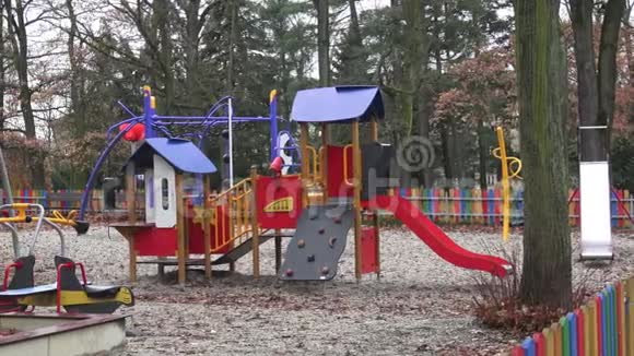 五颜六色的儿童游乐场活动在公共公园被树木包围视频的预览图