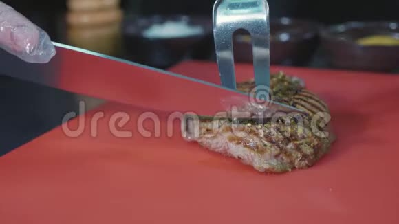 在商业厨房切熟猪肉牛排的厨师视频的预览图