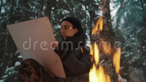 坐在森林篝火旁画画布的年轻艺术家视频的预览图