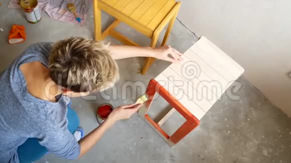 一个女孩在画椅子用你自己的手在公寓里修理视频的预览图