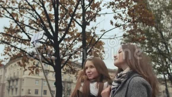 两个年轻的女孩朋友在一个城市的街道上做自我秋天视频的预览图