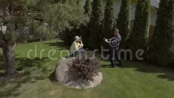 可爱的男人在花园里给漂亮女人拍照视频的预览图