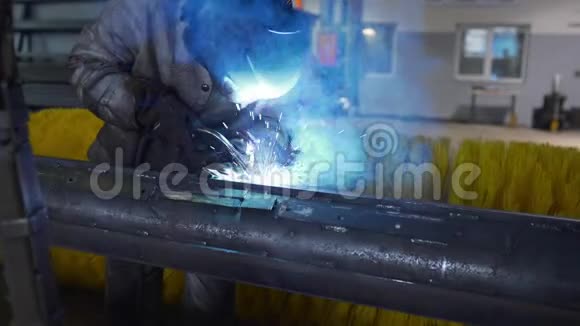 工厂车间内戴防护面罩和工作服的焊工焊接金属结构工厂内从事金属加工视频的预览图