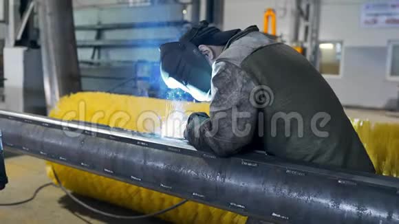工厂车间内戴防护面罩和工作服的焊工焊接金属结构工厂内从事金属加工视频的预览图