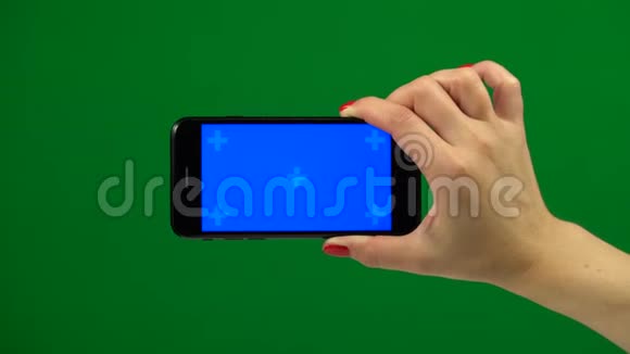 手拿着蓝色屏幕智能手机在绿色屏幕上视频的预览图