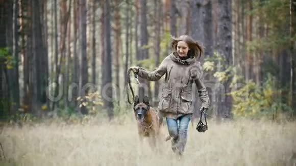 年轻可爱的快乐女人和她的狗玩德国牧羊犬在黄色的秋天公园狗跑在草地视频的预览图