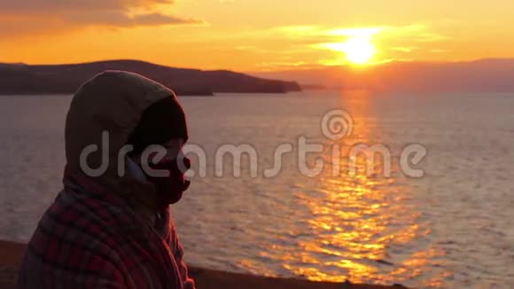 女孩坐在海边沉思美丽的金色夕阳视频的预览图