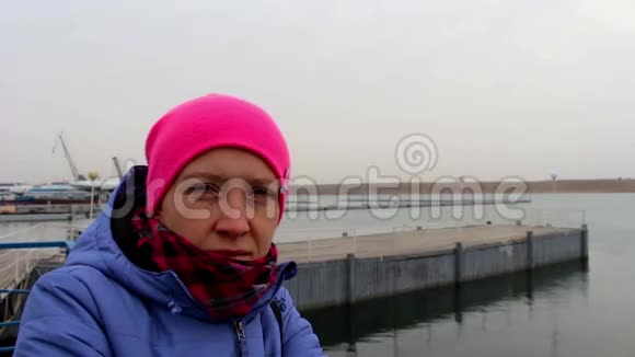 一个微笑的女孩在码头上的肖像在寒冷的阴天在秋天视频的预览图