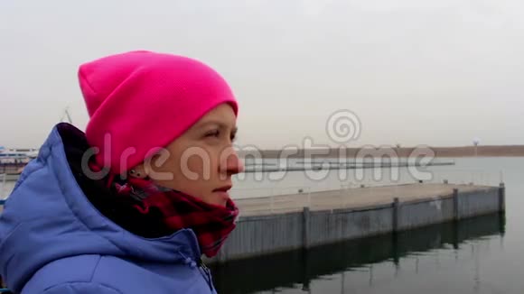 一个微笑的女孩在码头上的肖像在寒冷的阴天在秋天视频的预览图