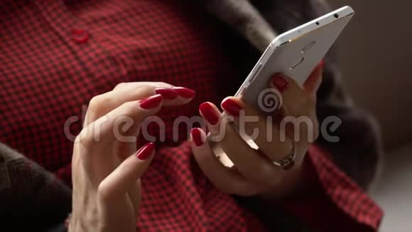 这位女士在智能手机上看信息那个穿红衬衫的女人坐在咖啡馆的小桌旁视频的预览图