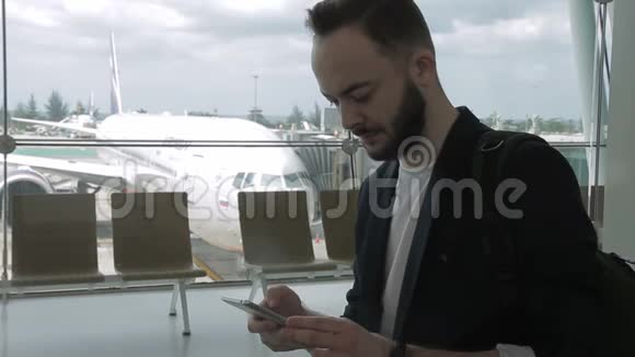 成年男子的肖像他正在机场使用他的智能手机视频的预览图