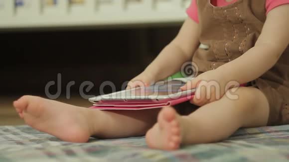 一个坐在地板上的小女孩用平板电脑触摸触摸屏上的手指视频的预览图