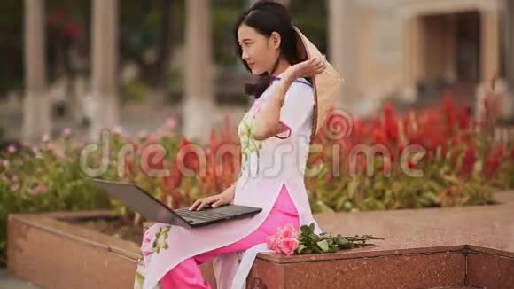 这位美丽的亚洲女孩在街上的笔记本电脑上说话穿着一件漂亮的民族服装敖岱视频的预览图