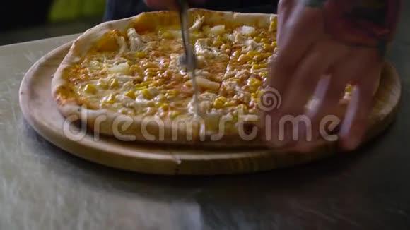 一个年轻的披萨师在餐厅的厨房准备披萨厨师用刀子把比萨饼切成碎片视频的预览图