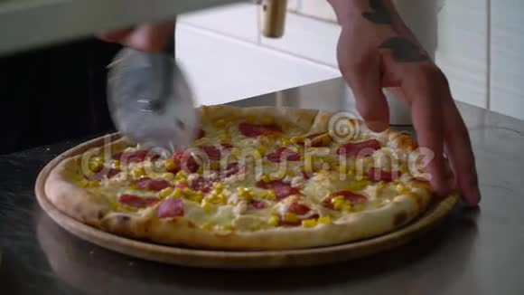 一个年轻的披萨师在餐厅的厨房准备披萨厨师用刀子把比萨饼切成碎片视频的预览图
