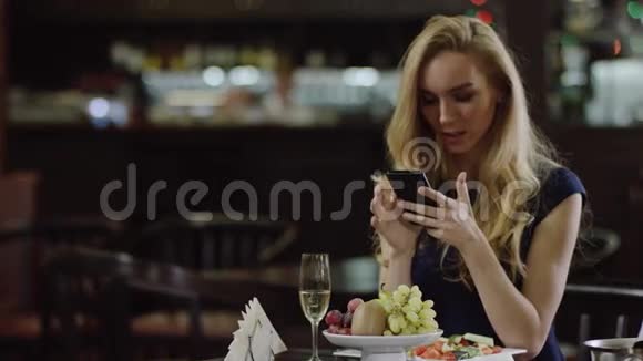 有智能手机的可爱女人坐在咖啡馆里视频的预览图