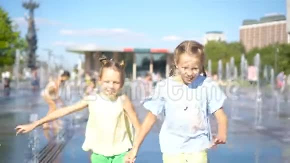 在炎热的阳光明媚的日子里小可爱的女孩在街头喷泉里玩得很开心视频的预览图