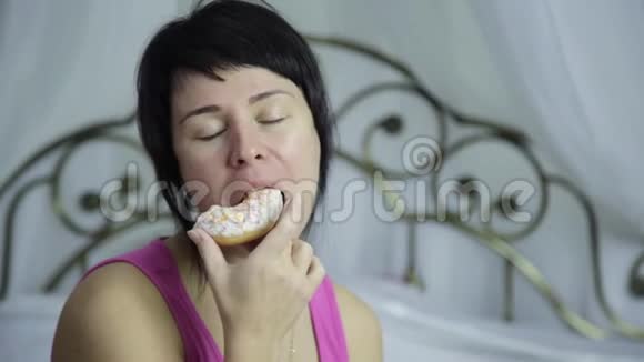 女人在床上吃甜甜圈早餐和垃圾食品视频的预览图