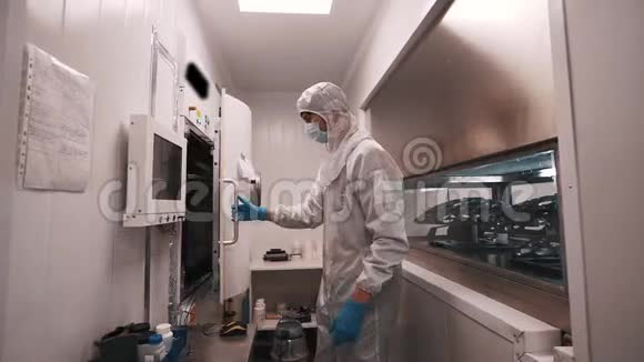 穿白色长袍和橡胶手套的科学家在实验室打开制造烤箱视频的预览图