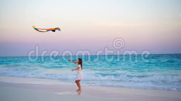 可爱的小女孩日落时在热带海滩放风筝孩子们在海边玩有沙滩玩具的孩子视频的预览图