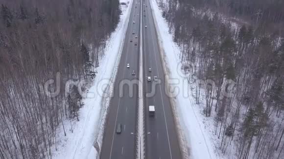 在冬季公路上行驶的汽车和卡车通过白雪森林的鸟瞰图视频的预览图