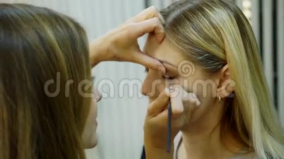 化妆师用一支黑色的眼睛铅笔画的那个女人是模特的女孩视频的预览图