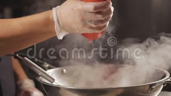 厨师在炒菜锅里倒入酱汁的特写慢动作视频的预览图