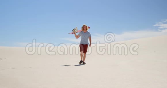 带着沙板在沙漠中行走的人视频的预览图