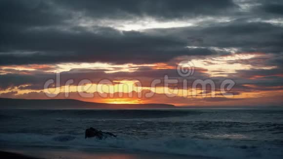 令人难以置信的美丽日落在海滩上石头上的波浪视频的预览图