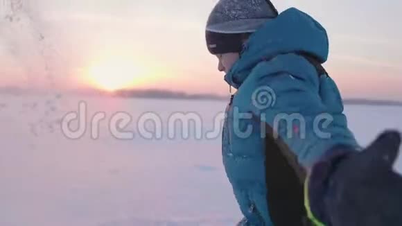 一个孩子在冬天户外玩耍跑步把雪扔到顶部美丽的日落户外运动视频的预览图