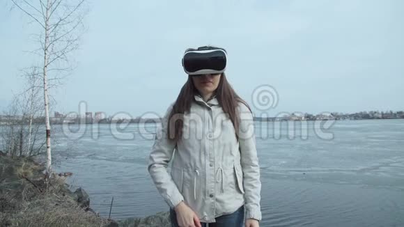 一个女人站在春天的池塘旁边用虚拟现实眼镜视频的预览图