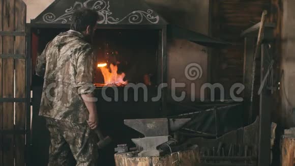 长胡子的青年铁匠在铁匠的铁砧上用火花烟火手工锻造铁水视频的预览图