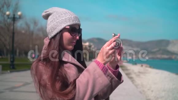 一个年轻的女孩戴着眼镜戴着帽子在春天的河堤上穿着外套视频的预览图