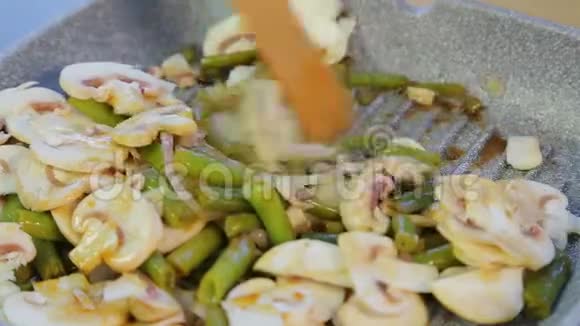 一个女人在煎锅里把绿豆和蘑菇混合在一起视频的预览图