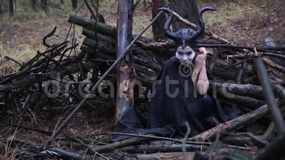 美丽的悲伤的女孩在图像中Maleficent坐在森林中的树枝上视频的预览图