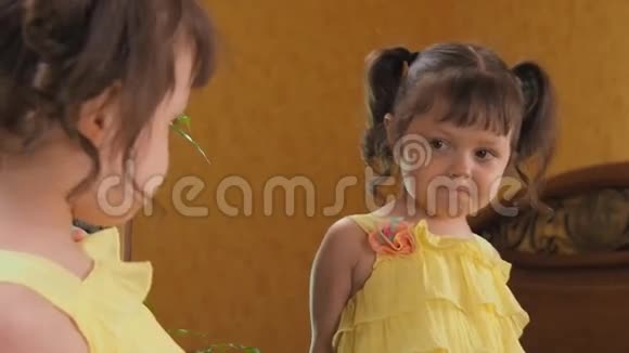 一个小女孩在照镜子一个头上有尾巴的漂亮女孩斜靠在镜子前一个穿黄色衣服的孩子视频的预览图