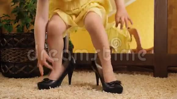 小女孩穿着高跟鞋摔倒了镜子前的孩子穿着大鞋一个穿着黄色衣服的漂亮孩子在镜子前穿着衣服视频的预览图