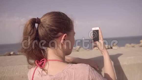 带着智能手机的女孩在拍摄海平面一大早慢动作视频的预览图