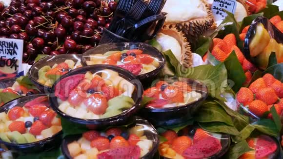 将不同的草莓水果芒果猕猴桃等混合在水果市场柜台上的塑料盘子里视频的预览图