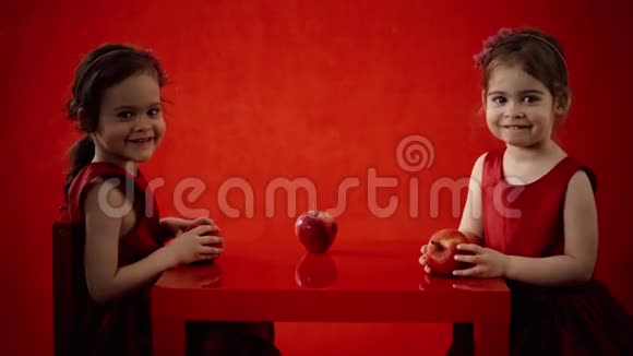 两个小女孩在红桌子上吃苹果视频的预览图