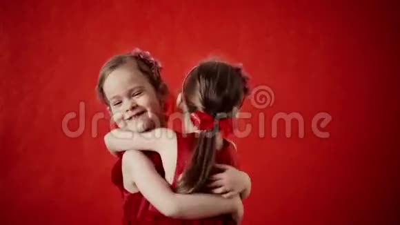 两个小女孩在红色背景上拥抱视频的预览图