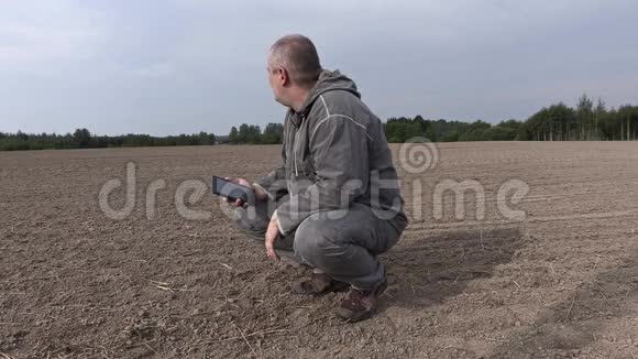 农民在田间检查土壤在智能手机上交谈视频的预览图